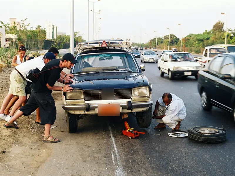 People helping change a flat tire at the roadside