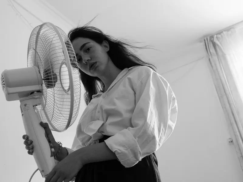 A woman cooling off in front of a fan
