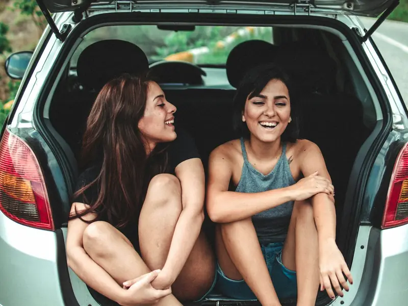 Two friends laughing in the back of a car